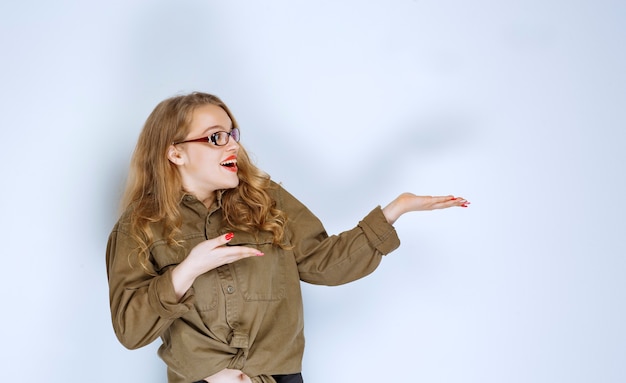 Foto grátis menina loira apontando para alguém à direita.