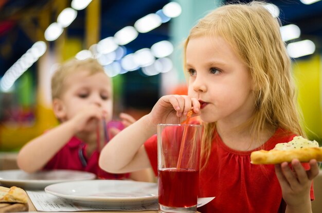 Menina loira bebendo suco