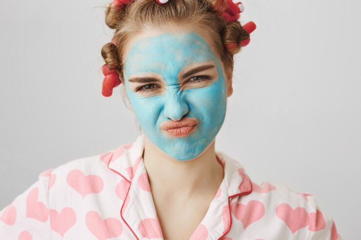 Foto grátis menina loira bonita e boba com máscara facial e babadores de cabelo franzido