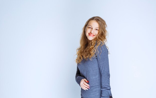 Menina loira com cabelos cacheados, posando com uma camisola índigo.