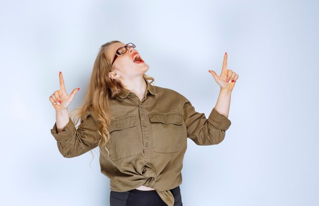 Menina loira com camisa verde apontando acima.