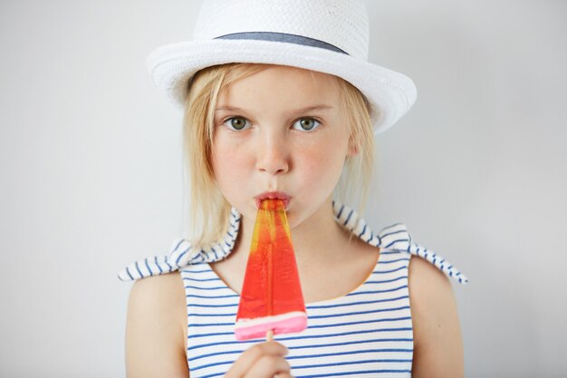 Foto grátis menina loira de chapéu branco tomando sorvete