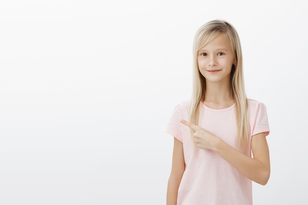 Foto grátis menina loira fofa feliz apontando o dedo para a esquerda