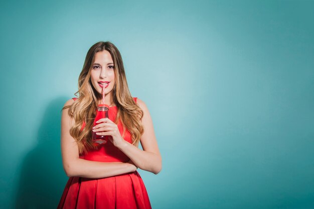 Menina loira posando com suco vermelho