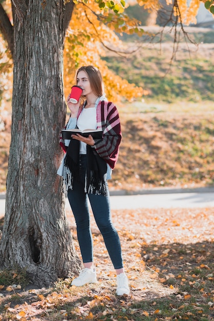 Foto grátis menina loira segurando um caderno e tomando café