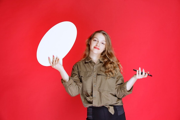 Menina loira segurando um ideaboard oval em uma mão e um smartphone na outra mão.