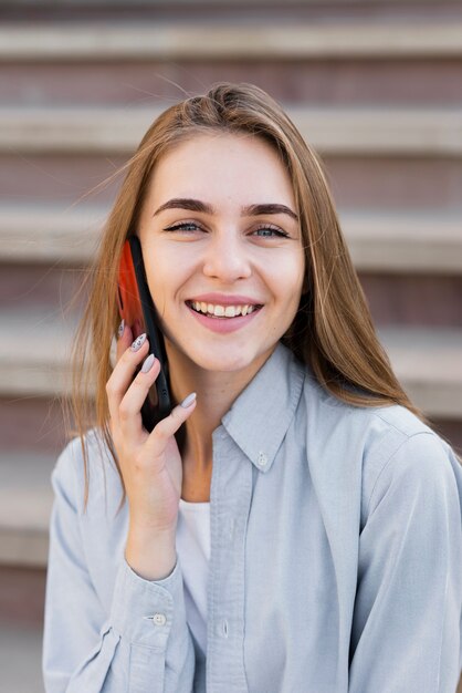 Menina loira sorridente, falando no telefone