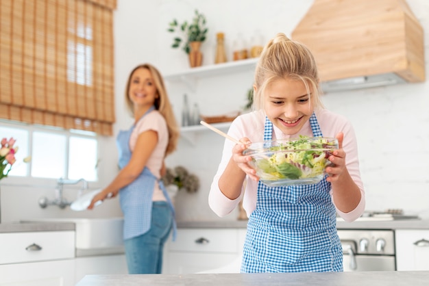 Menina loira sorridente, olhando para a salada