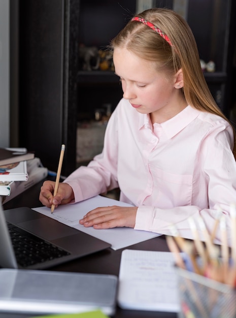 Foto grátis menina loira tomando notas na aula on-line