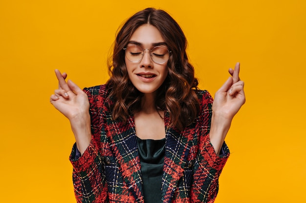 Menina moderna com cabelo castanho e roupa listrada cruzando o dedo na parede isolada