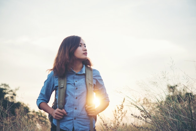 menina moderno novo com a trouxa que anda através do campo do verão.