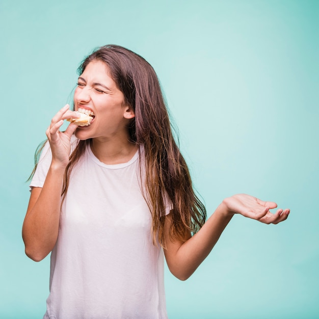 Menina morena comendo pastelaria