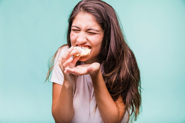 Menina morena comendo pastelaria