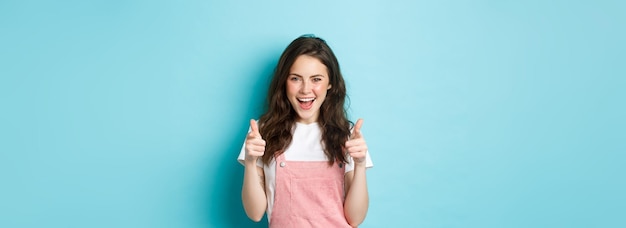 Foto grátis menina morena confiante e alegre diz sim apontando dedos para a câmera e parecendo atrevida elogiando y