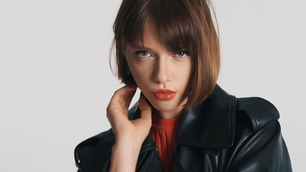 Menina morena de moda com cabelo bob e lábios vermelhos olhando sério sobre fundo branco. Modelo profissional posando em estúdio