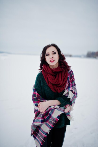 Menina morena de suéter verde e cachecol vermelho com lago congelado ao ar livre na noite de inverno