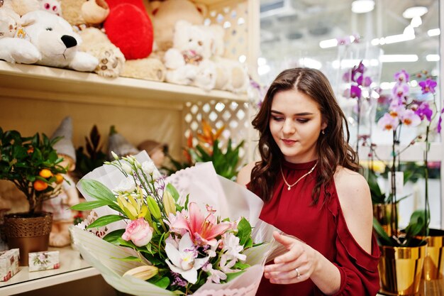 Menina morena de vermelho compra flores na loja de flores