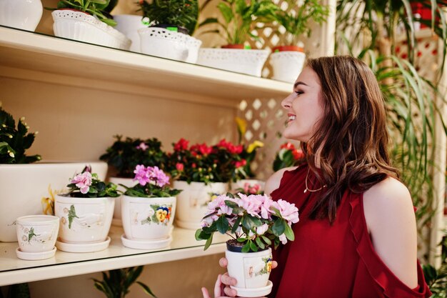 Menina morena de vermelho compra flores na loja de flores