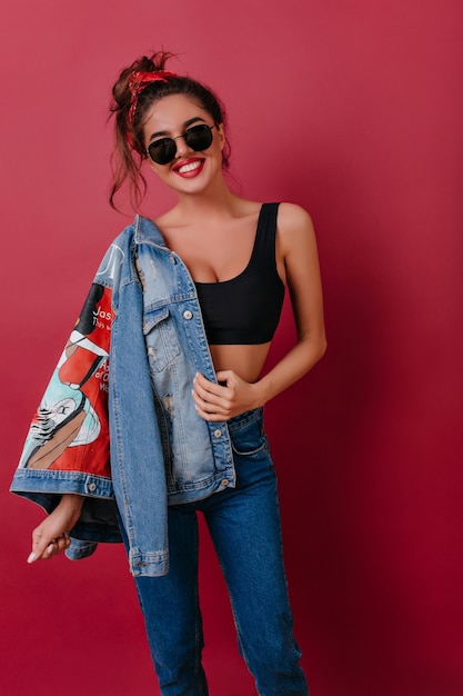 Foto grátis menina morena emocional com sorriso fofo posando com nova jaqueta jeans