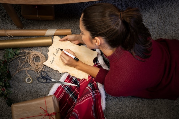 Foto grátis menina morena escrevendo uma carta para o papai noel