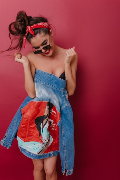 Foto grátis menina morena espetacular segurando uma jaqueta jeans decorada enquanto posa