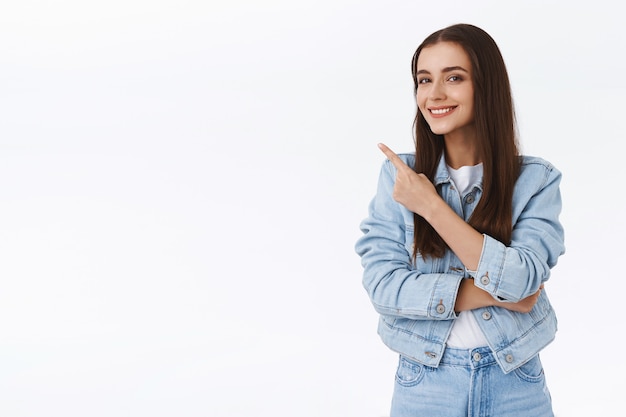 Menina morena jovem inteligente, bonita e criativa dando conselhos, apontando para o canto superior esquerdo, sugerir promoção, sorrindo satisfeito, aprovar algum produto, fundo branco permanente