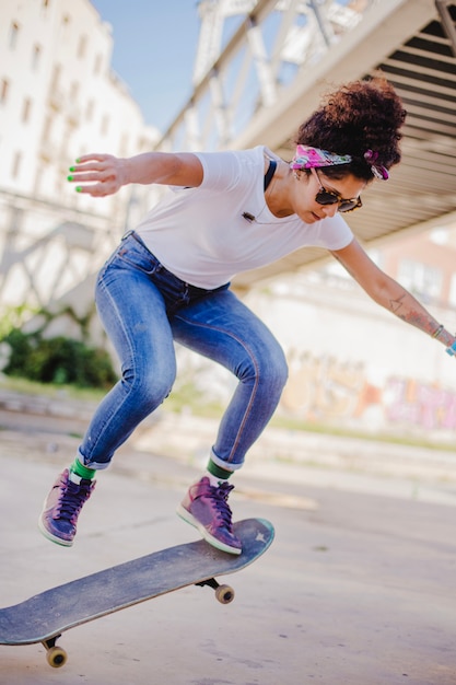 Menina morena montando skate fazendo truques