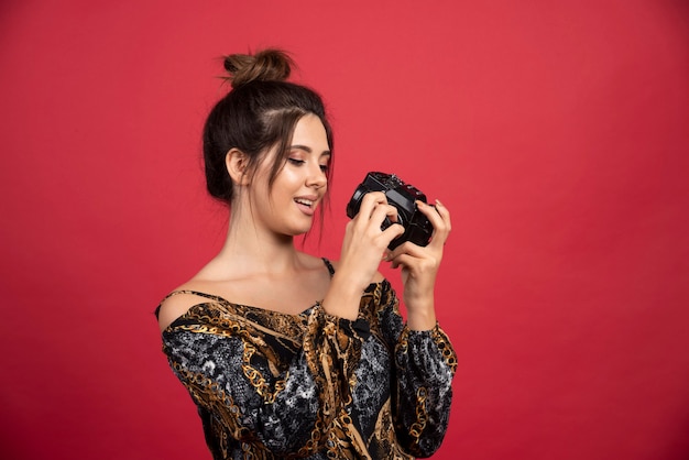 Menina morena segurando uma câmera dslr profissional e pensando.