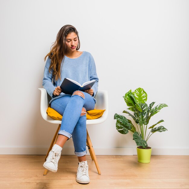 Menina morena sentada lendo um livro