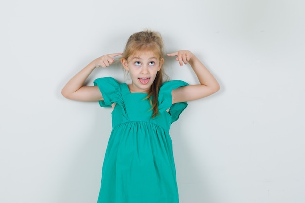 Foto grátis menina mostrando a língua com gesto de dedo em vestido verde