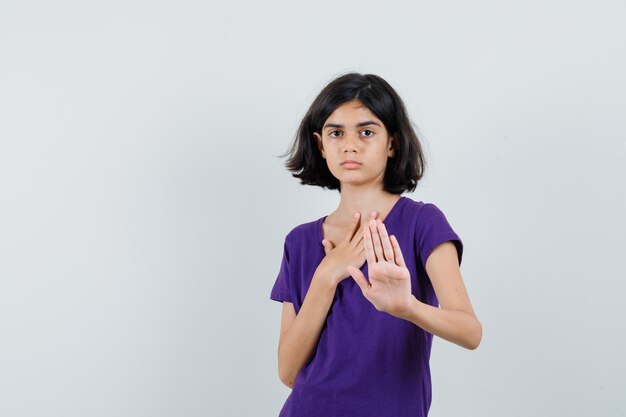 Menina mostrando gesto de parada em t-shirt e parecendo irritada.
