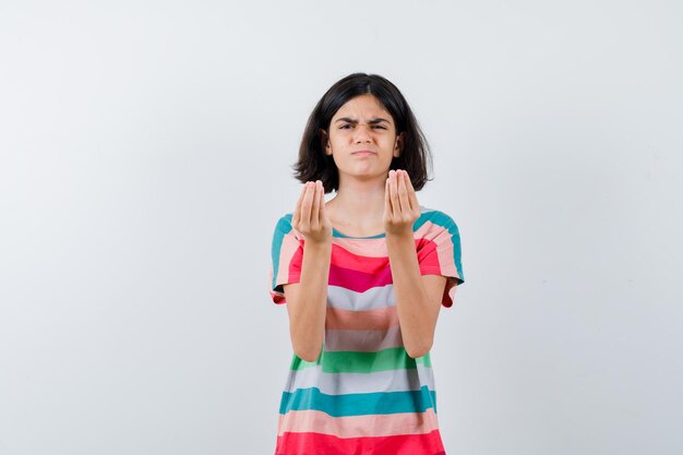 Menina mostrando gesto italiano, fazendo careta em camiseta, jeans e parecendo descontente. vista frontal.