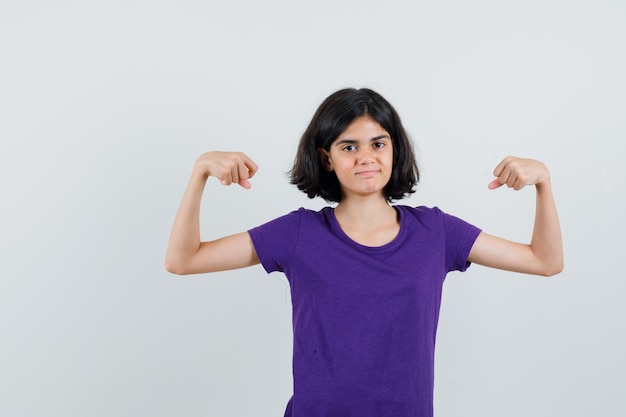 Menina mostrando os músculos dos braços em t-shirt e parecendo confiante.