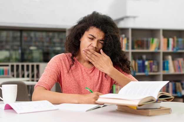 Menina na biblioteca, sentindo-se sonolento