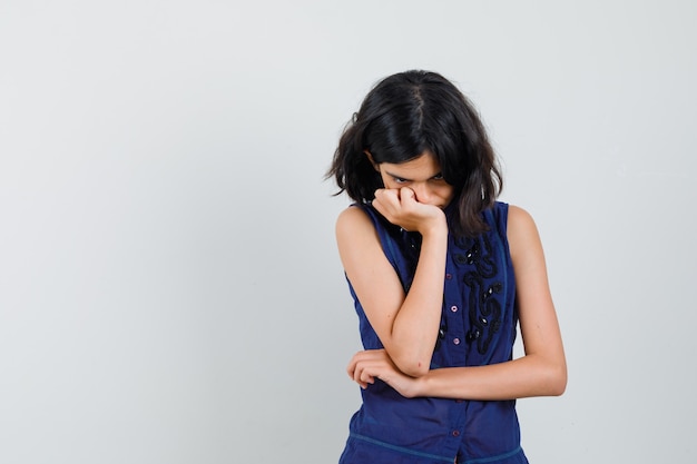 Foto grátis menina na blusa azul, olhando para baixo em pose pensativa e parecendo triste.