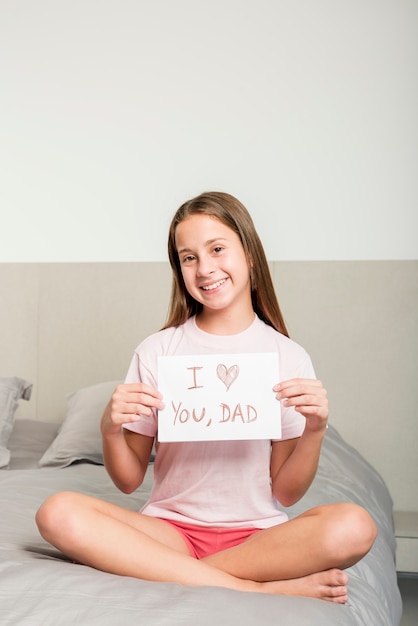 Menina na cama com papel para o dia dos pais