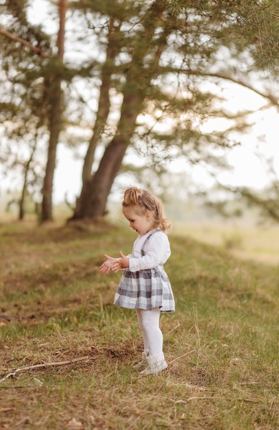 Menina na floresta. Em uma estrada da floresta entre os pinheiros.