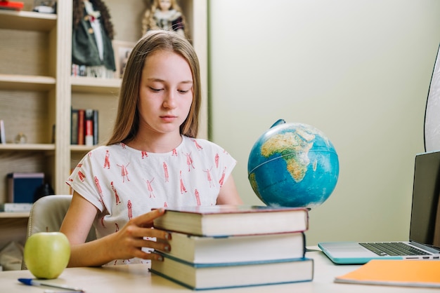 Menina na mesa com livros empilhados