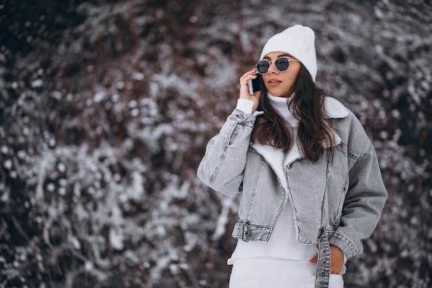 Menina na moda jovem em um parque de inverno usando o telefone