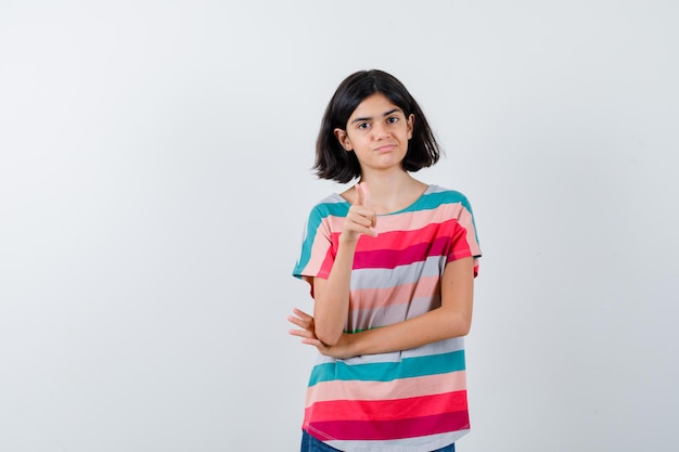 Foto grátis menina na t-shirt, apontando e olhando confiante, vista frontal.