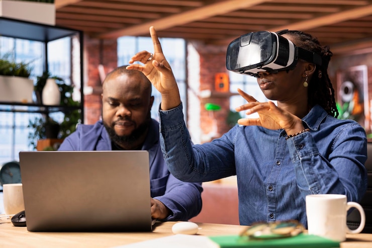 Foto grátis menina negra se envolve com a realidade virtual enquanto o parceiro trabalha no laptop na mesa