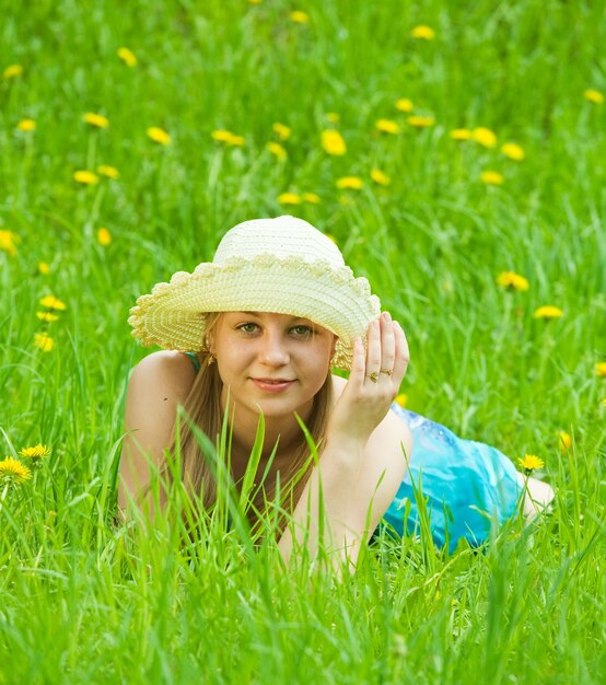 Menina no chapéu que relaxa na grama