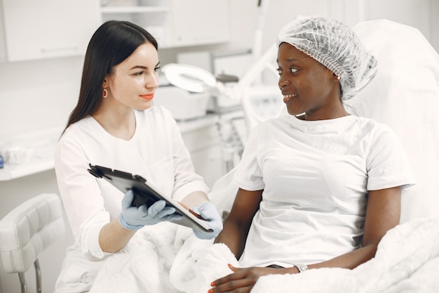 Menina no consultório médico. Mulher africana no sofá. Consulta médica.