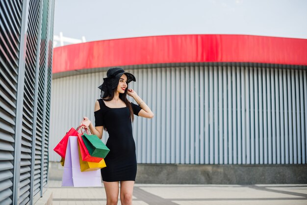 Menina no vestido preto segurando sacos de pé