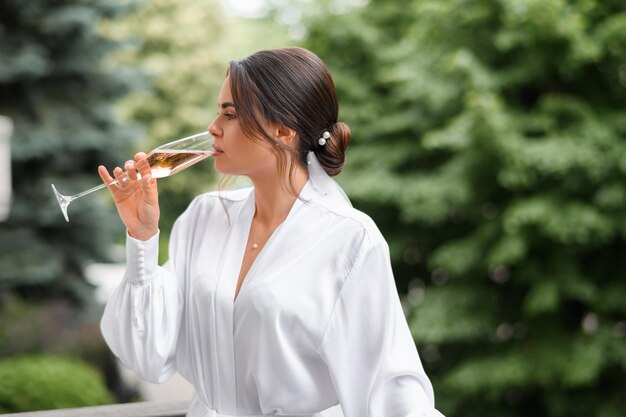 Menina noiva bebendo champanhe ao ar livre