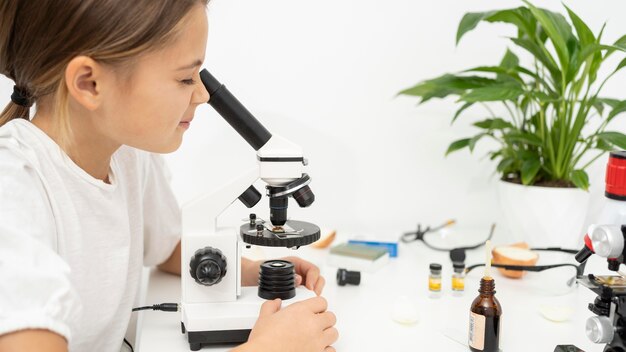 Menina olhando no microscópio