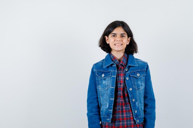 Menina olhando para a câmera de camisa, jaqueta e olhando feliz, vista frontal.