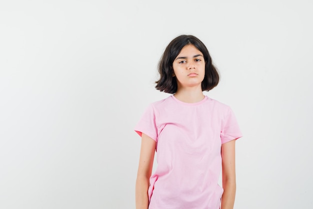 Menina olhando para a frente em t-shirt rosa e parecendo sombrio. vista frontal.