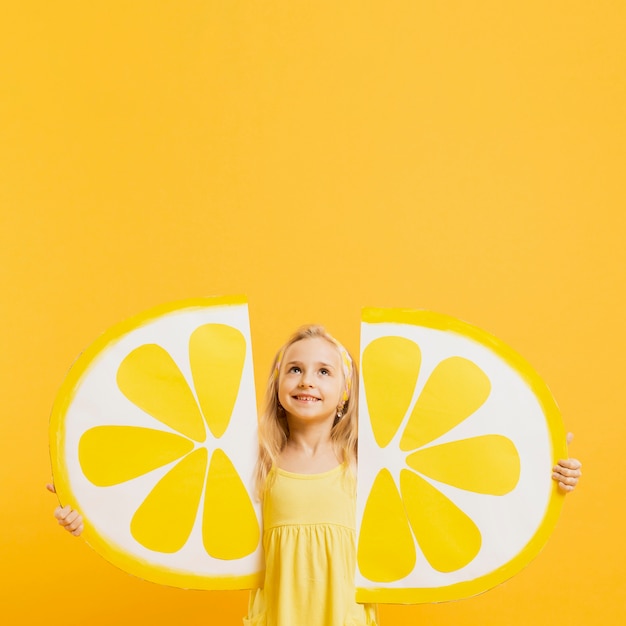 Foto grátis menina olhando para cima, mantendo decorações de fatias de limão