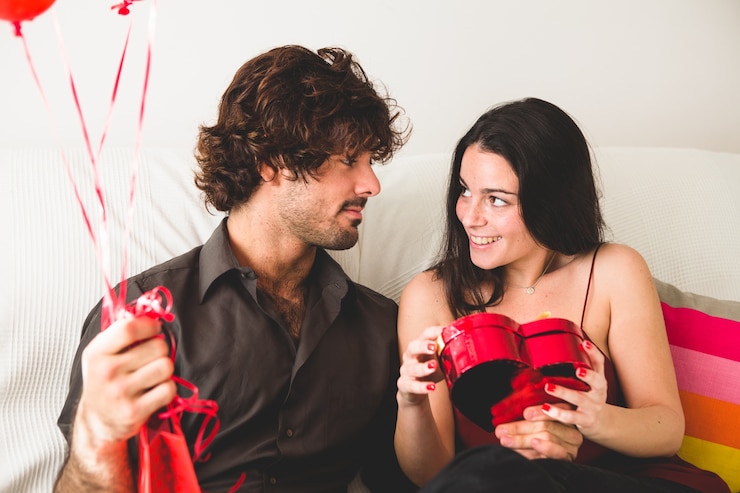 Foto grátis menina olhando para o namorado ao abrir uma caixa de chocolates